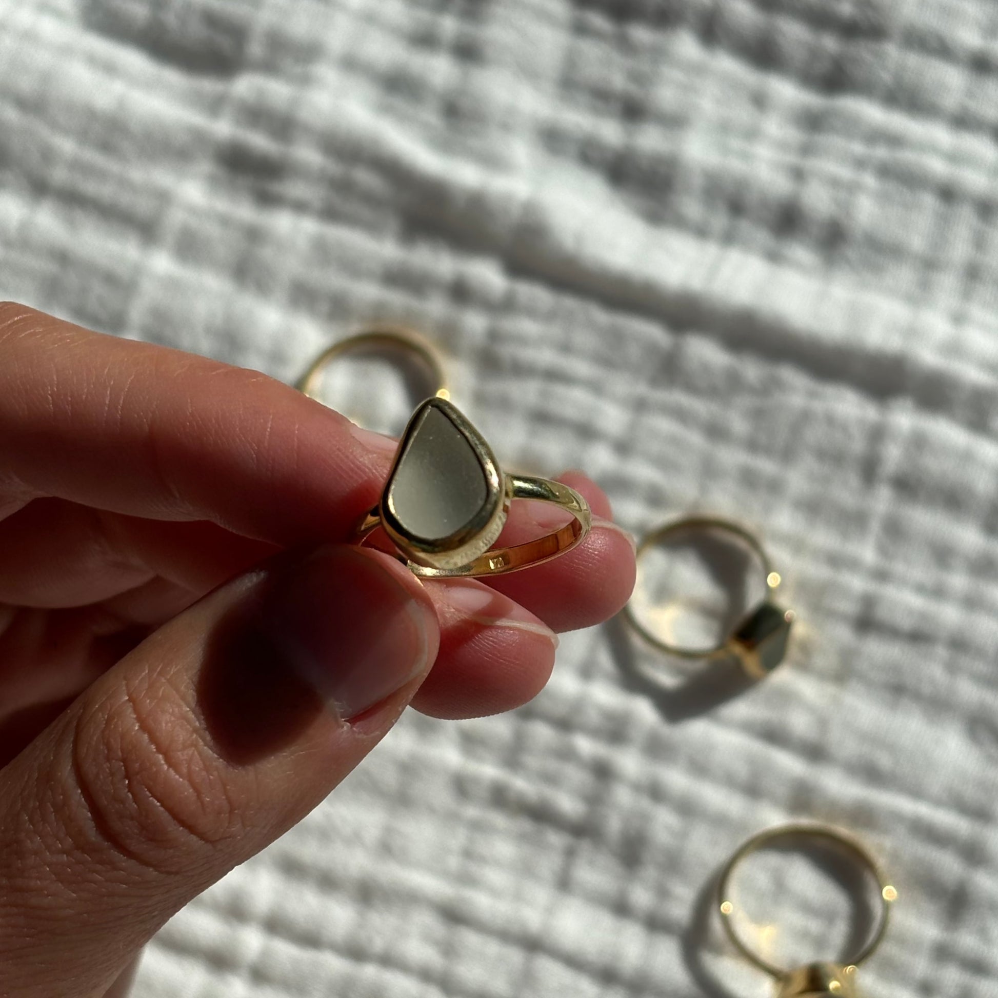 picking up a white sea glass ring from a white background
