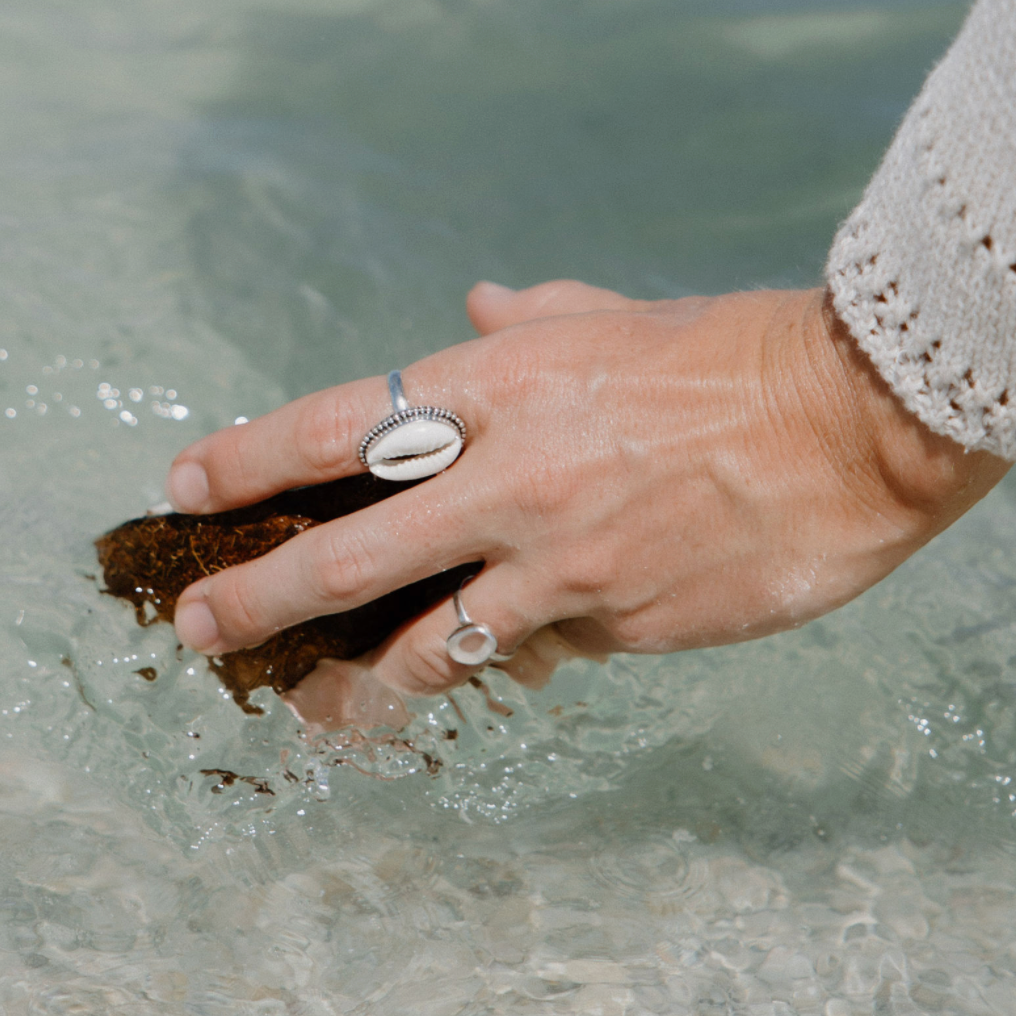 dipping a coconut in florida water with a sea glass and shell ring on