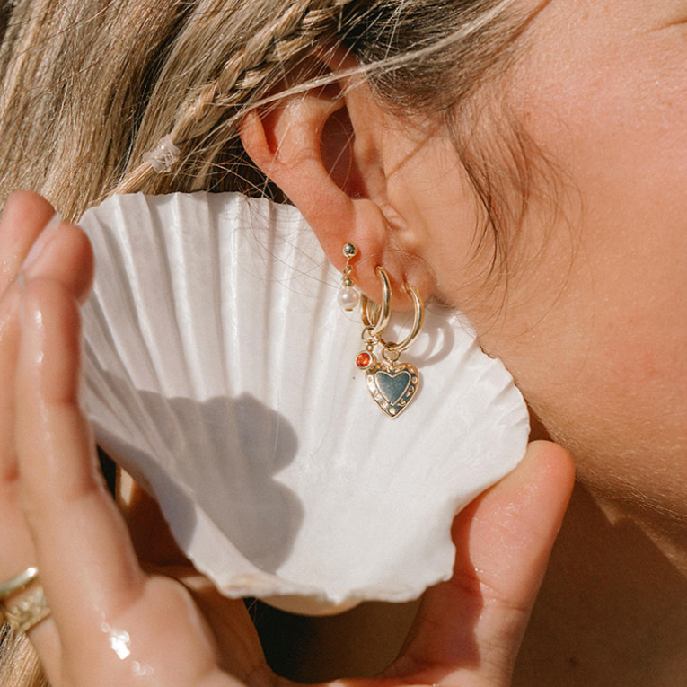 shell cupping a gold earring stack